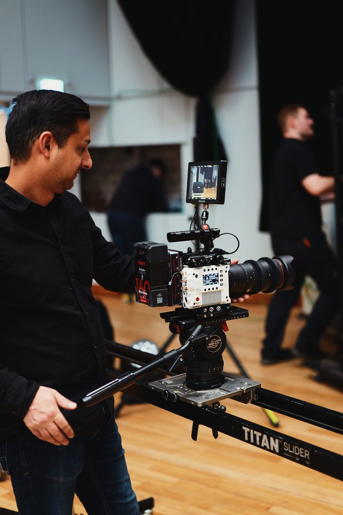 Mann bedient eine Filmkamera auf einem Slider im Studio.